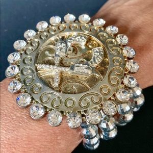 Silver bracelet with two guns on buckle of emblem.